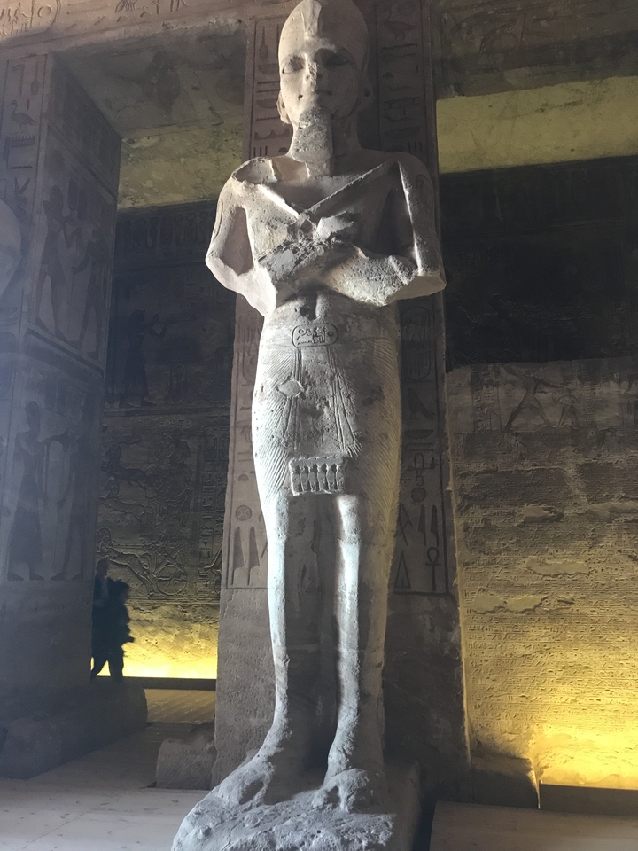 Statue ancienne dans l'intérieur d'un temple faiblement éclairé avec des sculptures.