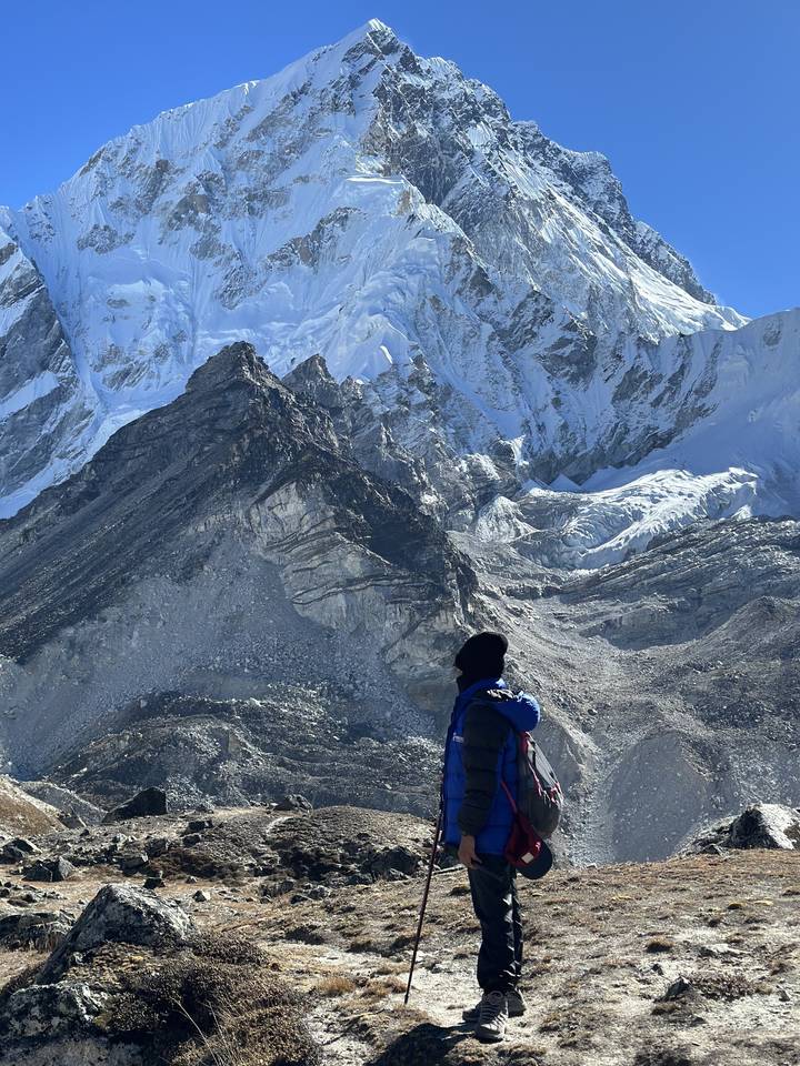 Randonneur dans un terrain montagneux avec des sommets enneigés.