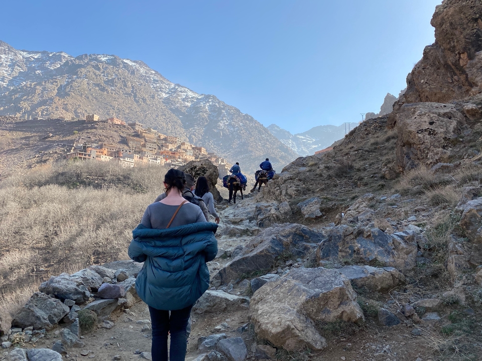 Des randonneurs et des ânes sur un sentier de montagne rocheux.