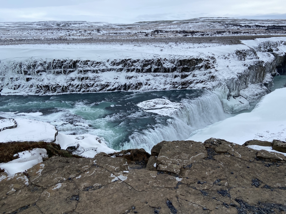 Powerful waterfall surrounded by snowy landscape.