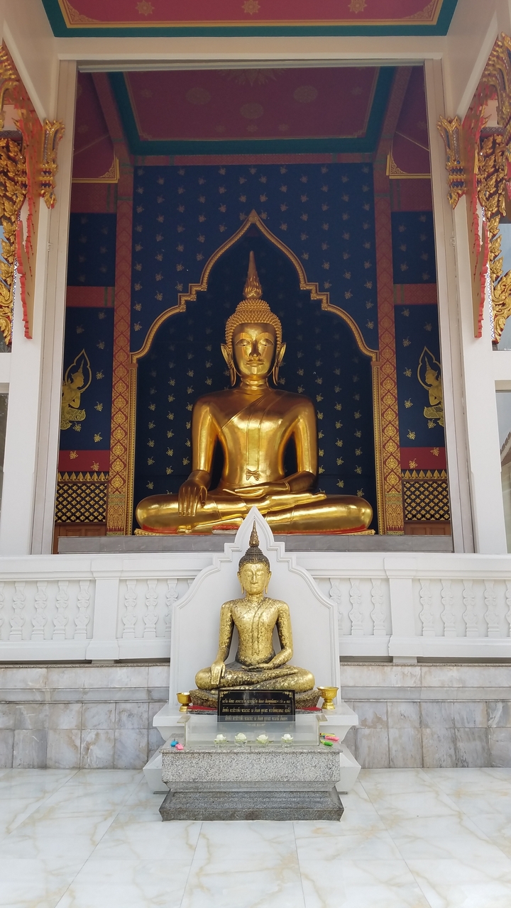 Golden Buddha statue seated against an ornate backdrop.