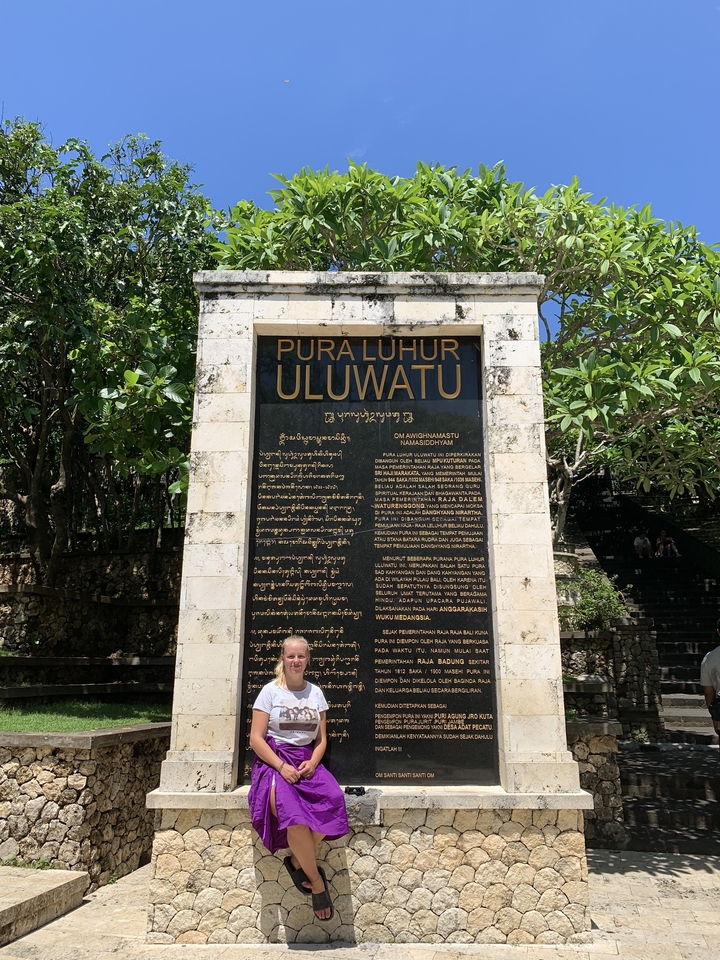 Personne debout devant un panneau pour Pura Luhur Uluwatu.