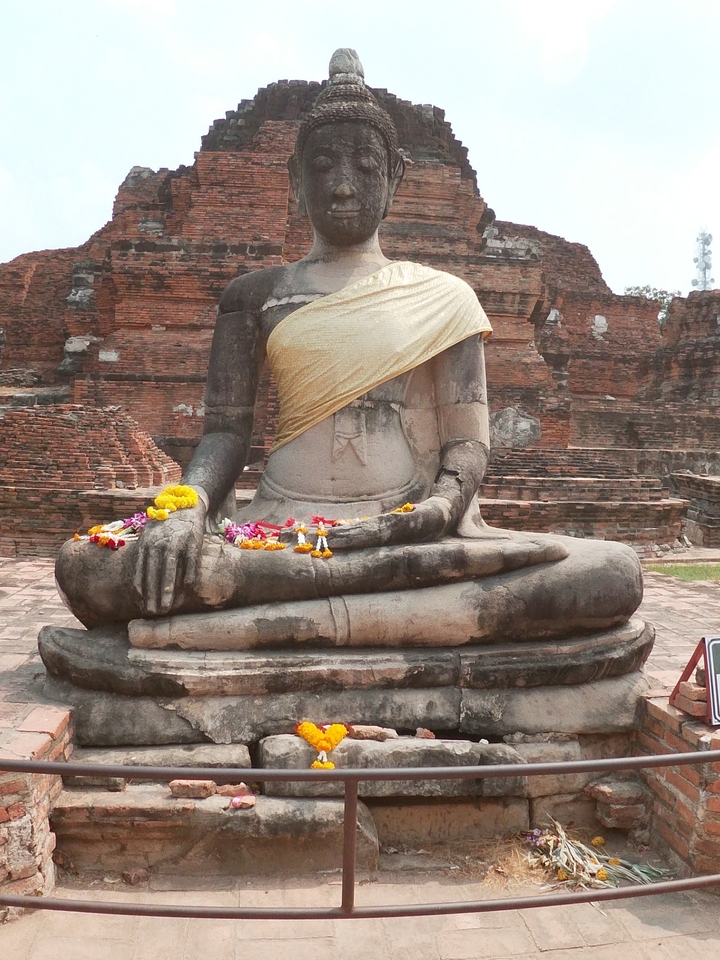 Ancienne statue assise avec des fleurs sur ses genoux.