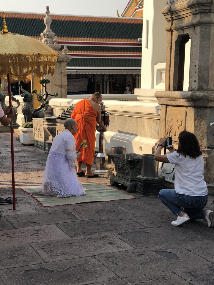 Des moines effectuant un rituel dans un temple avec un photographe capturant le moment.