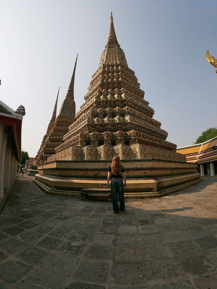 Femme debout devant des pagodes décoratives dans une cour de temple.