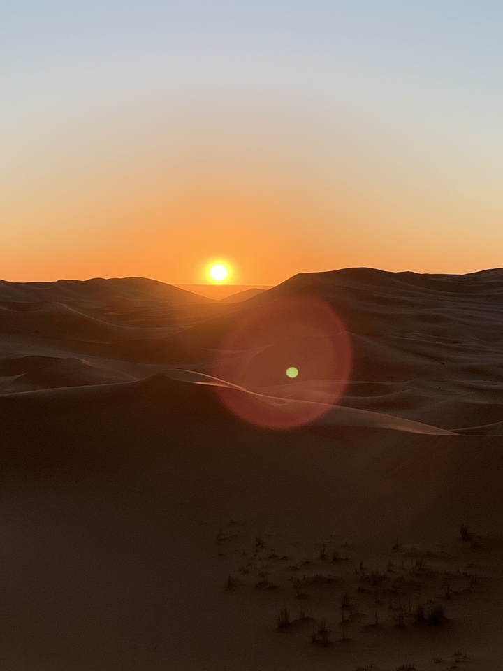 Coucher de soleil sur les dunes de sable dans un environnement désertique.