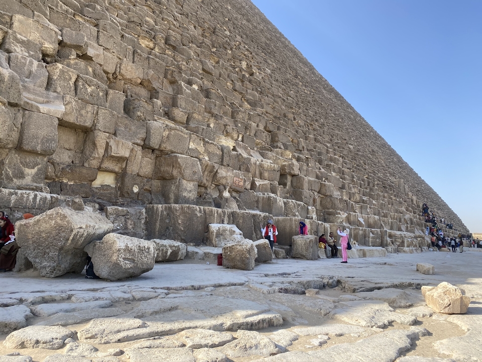 Massive stone blocks form the base of the Great Pyramid as visitors mill around