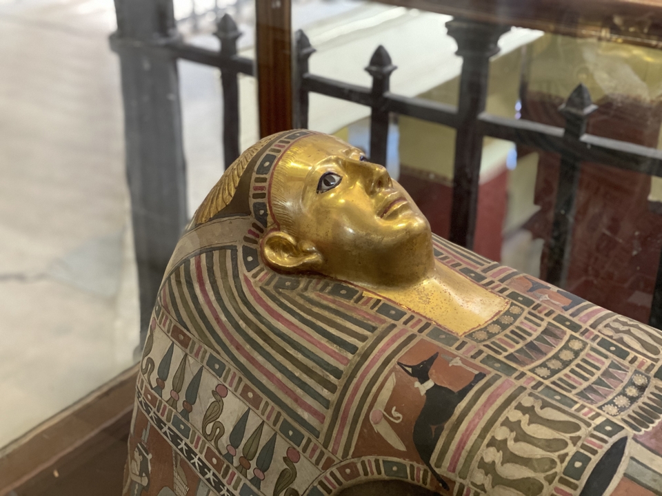 Close-up of an ancient gilded sarcophagus on display behind glass