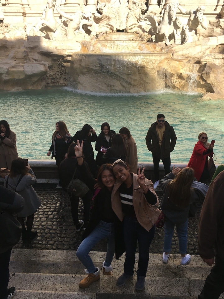 Crowds gather at the edge of the Trevi Fountain with turquoise water shimmering