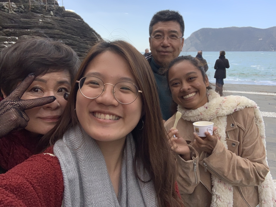 Smiling group selfie with seaside promenade and blue water in the background