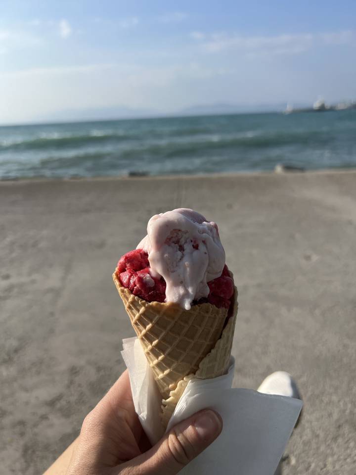 Cornet de glace tenu avec un arrière-plan de bord de mer.