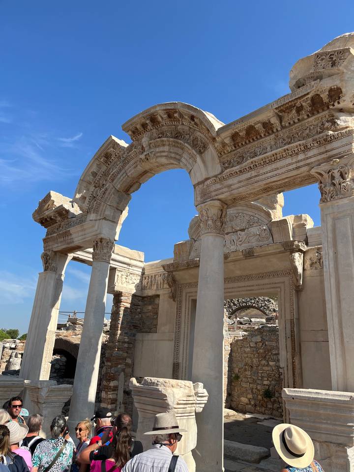 Des touristes explorant des ruines archéologiques avec des colonnes ornées.