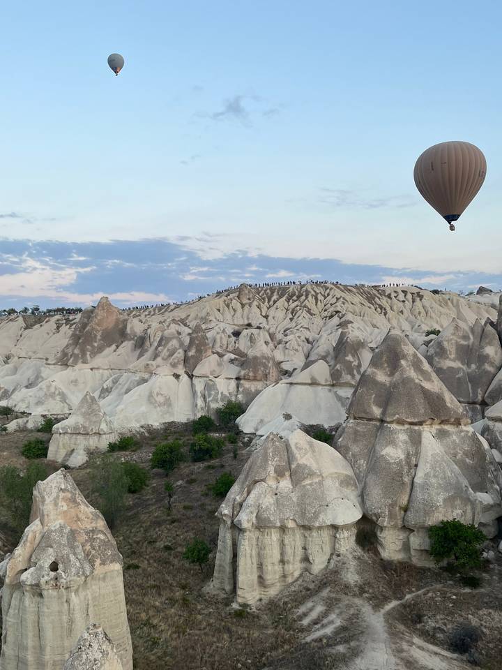 Montgolfières au-dessus d'un paysage rocheux sous un ciel dégagé.