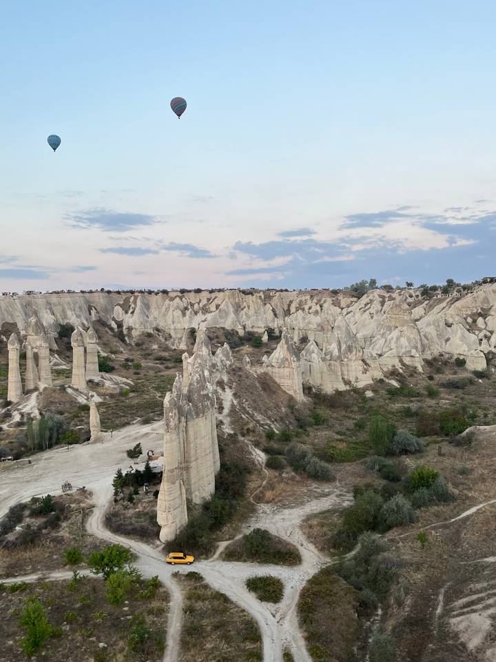 Montgolfières au-dessus d'un terrain rocheux avec un véhicule sur un sentier.