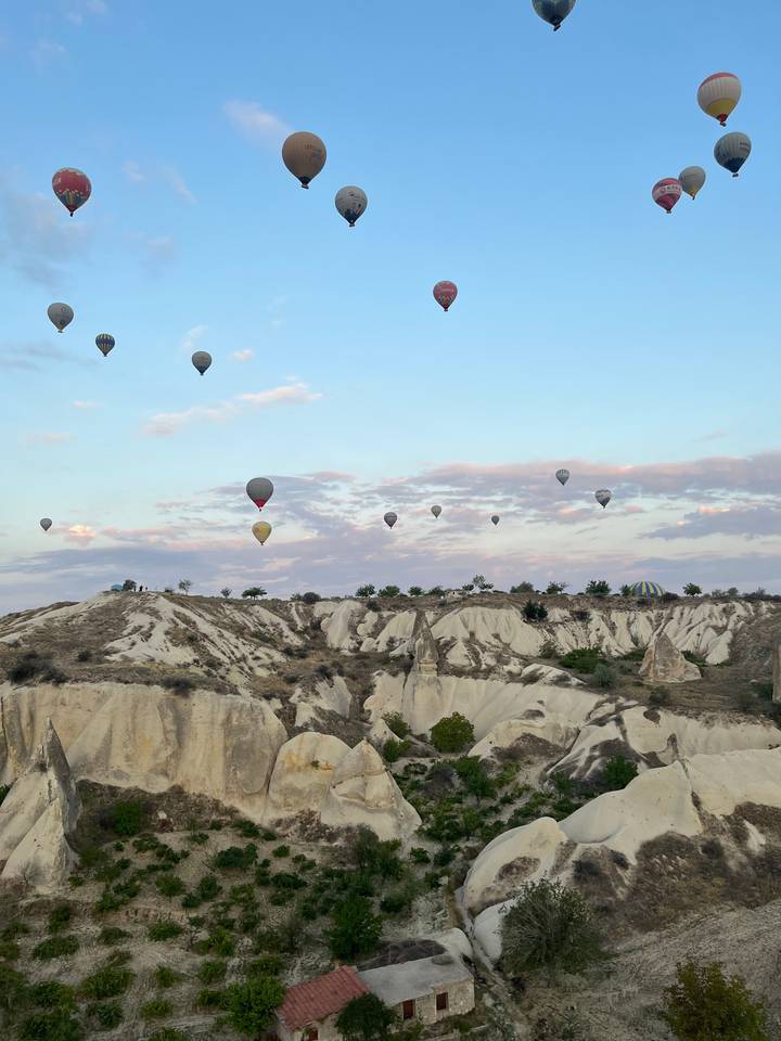Montgolfières dans un ciel plein de nuages au-dessus d'un terrain rocheux.