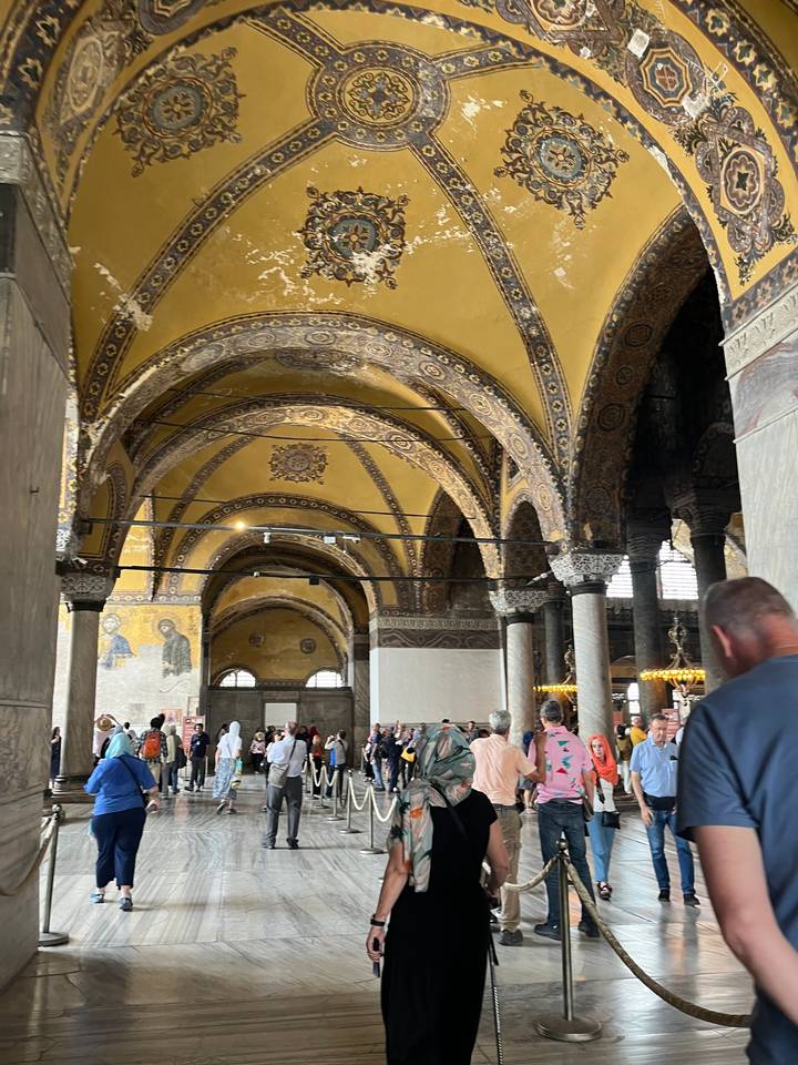 Visiteurs à l'intérieur d'un grand bâtiment historique aux plafonds ornementés.
