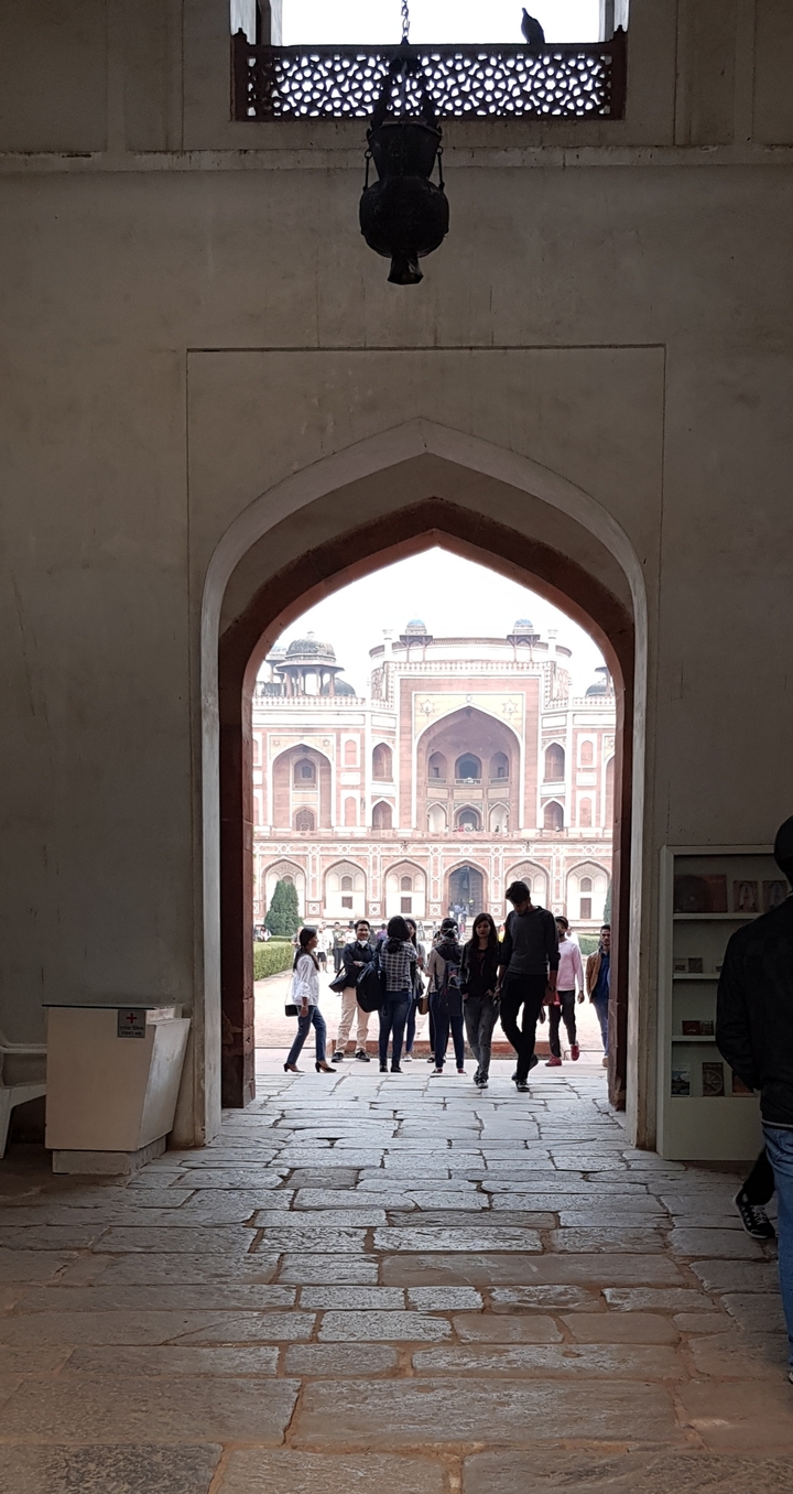 Vue à travers une arche d'un bâtiment historique rouge.