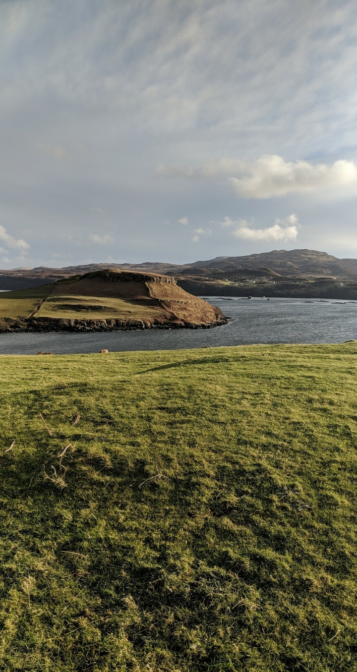 Paysage côtier avec des collines ondulantes et un plan d'eau.