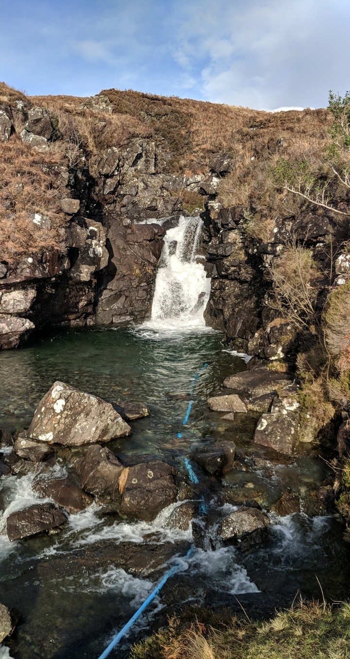 Cascade dans un bassin limpide entouré de rochers.