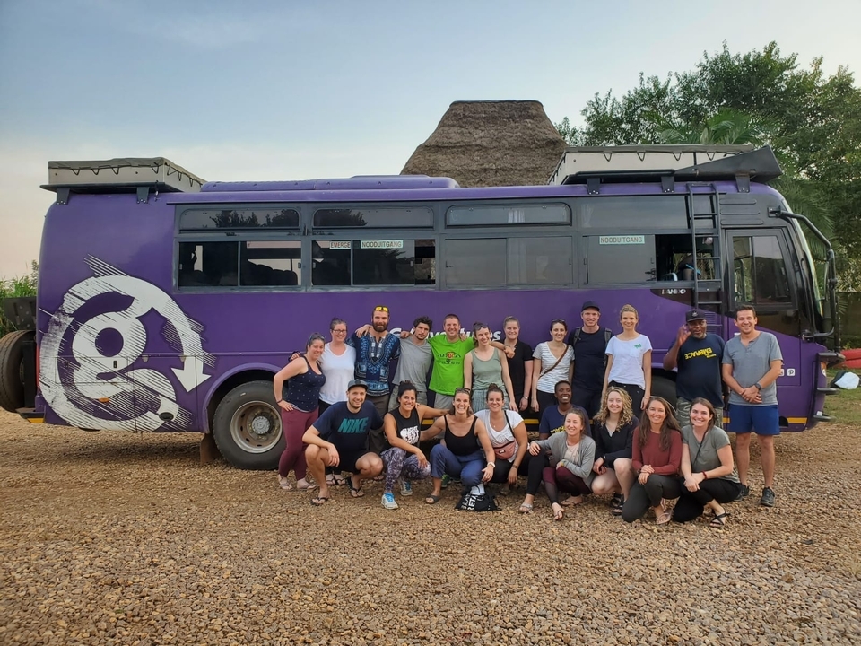 Groupe de personnes posant devant un autocar de tourisme violet.