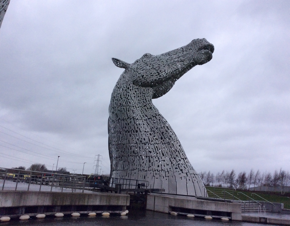 Une grande sculpture de tête de cheval à l'extérieur sous un ciel nuageux.