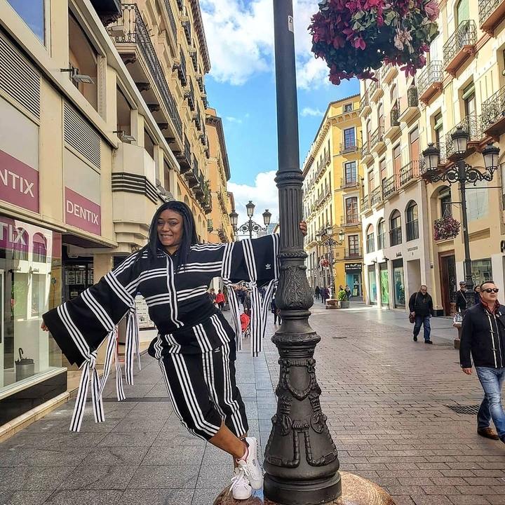 Une femme souriante qui pose avec un lampadaire dans une rue animée.