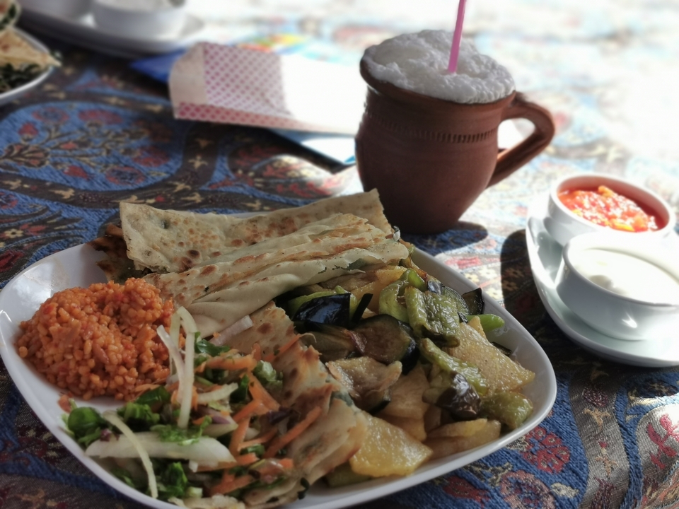 Une assiette de cuisine turque avec une variété de plats et une boisson mousseuse.