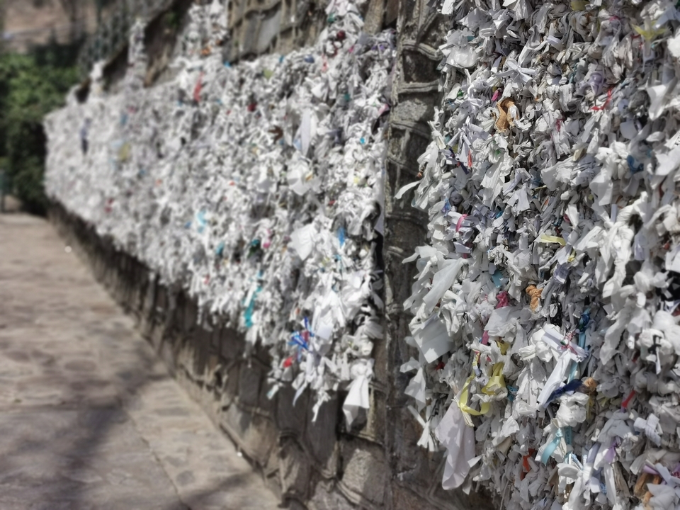 Un mur couvert de notes et de bouts de papier, possiblement un mur à souhaits.