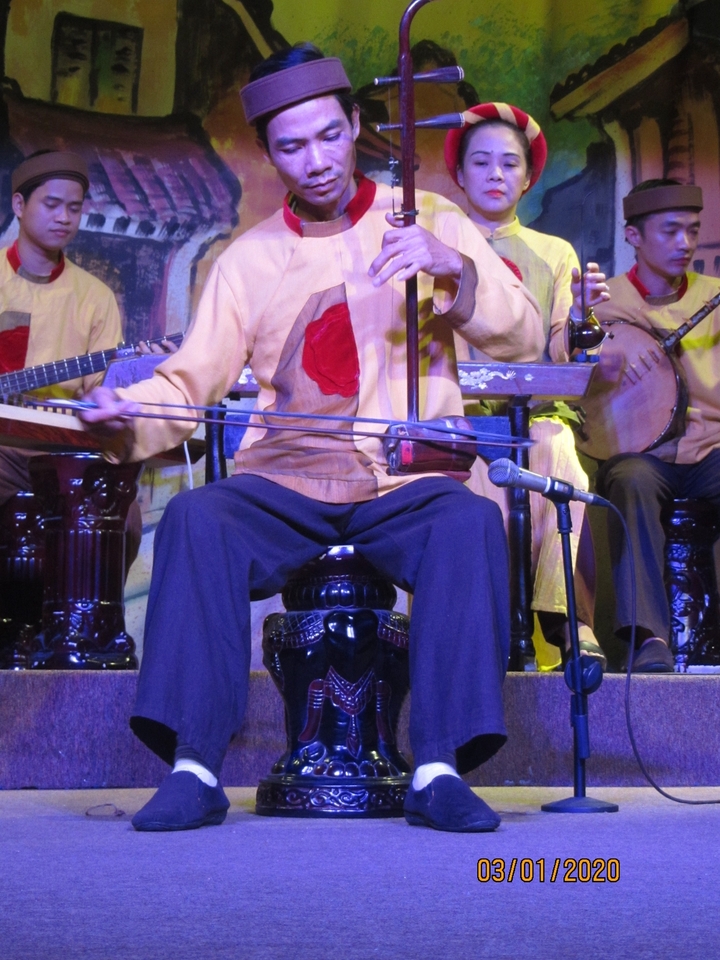 Un musicien jouant d'un instrument traditionnel vietnamien, se produisant sur scène.