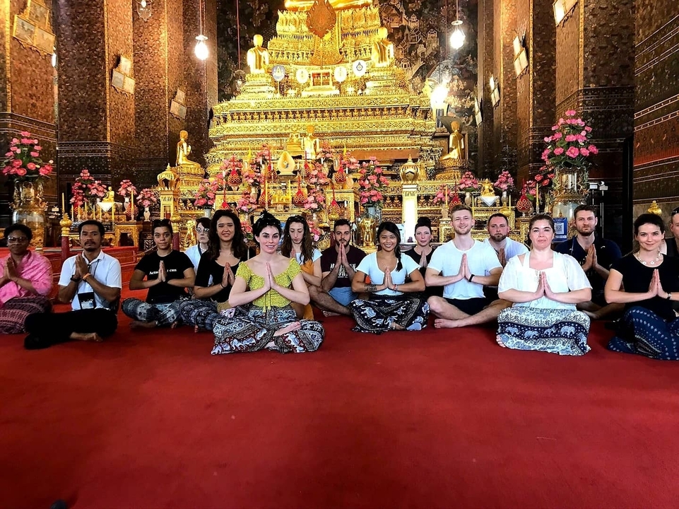 Group of people meditating inside a richly decorated temple.