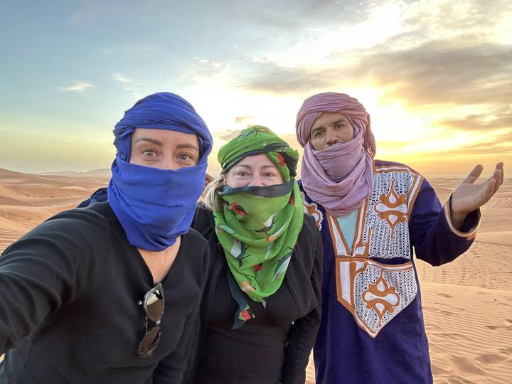 Trois personnes portant des foulards colorés dans un paysage désertique.