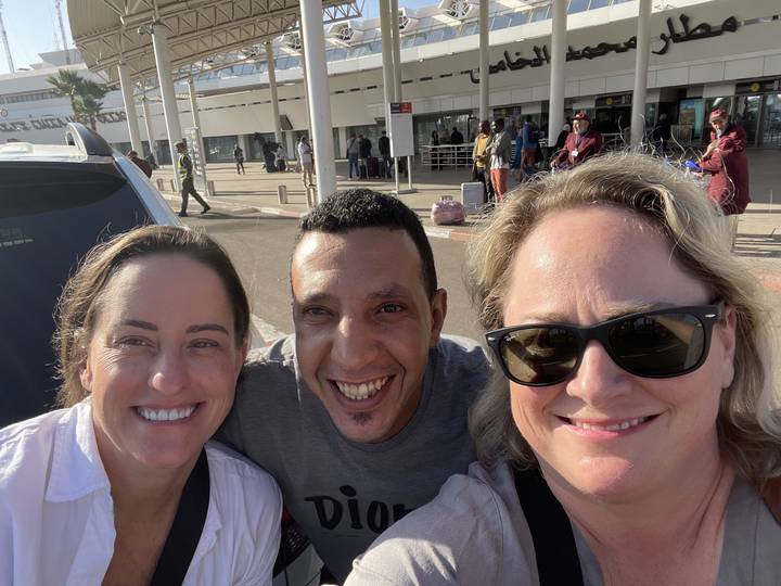 Trois personnes souriantes dans un lieu extérieur.