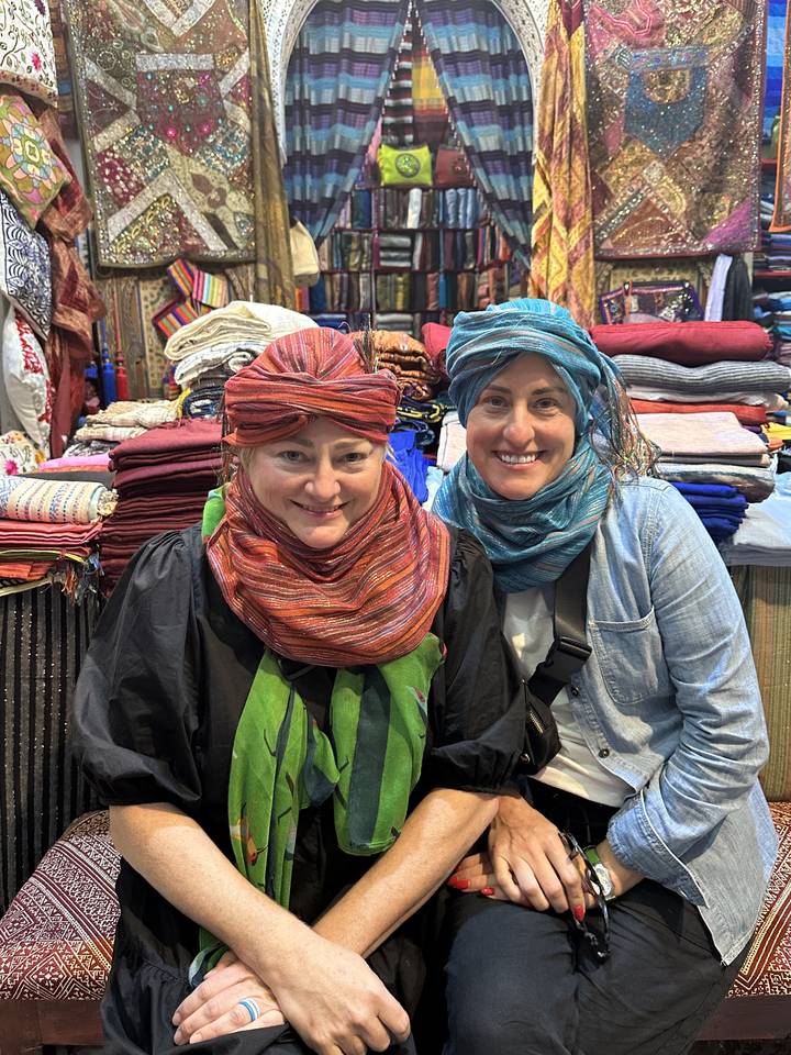 Deux personnes portant des foulards colorés dans un marché vibrant avec des textiles.