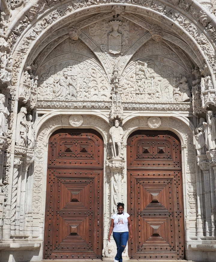 Façade en pierre ornée avec des sculptures complexes et deux grandes portes en bois.