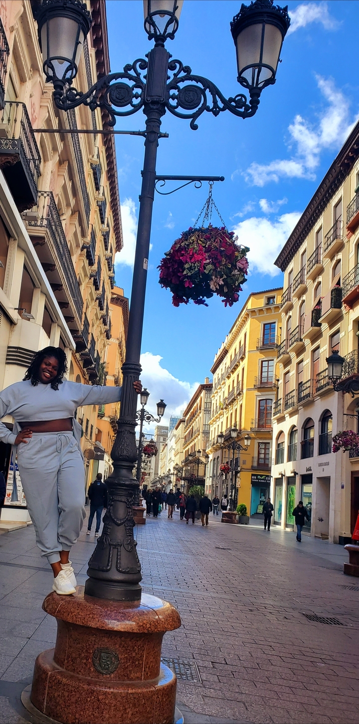 Personne qui pose dans une rue urbaine animée bordée de bâtiments traditionnels.