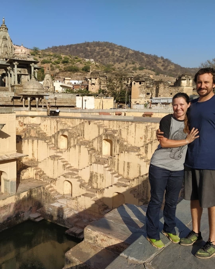 Couple posant devant une structure de puits à degrés ancien.
