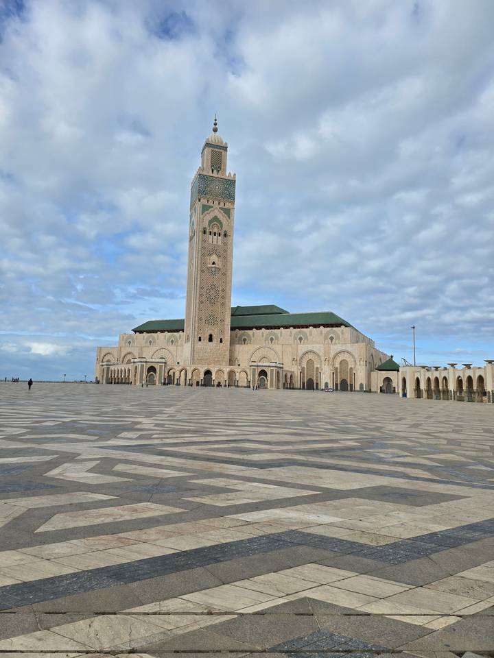 Grande mosquée avec un minaret élevé et un ciel nuageux.