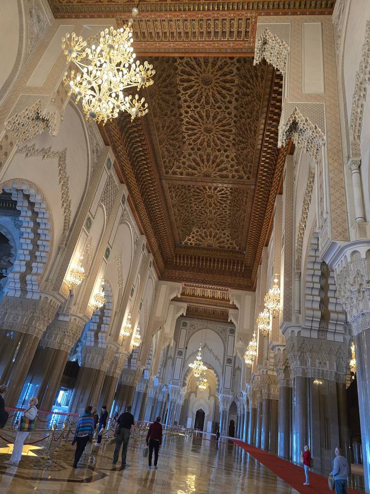 Intérieur d'une mosquée avec des lustres et des motifs complexes.