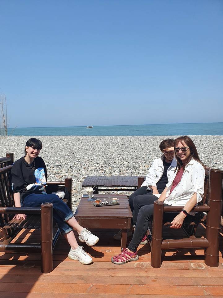 Des gens assis sur une plage de galets.