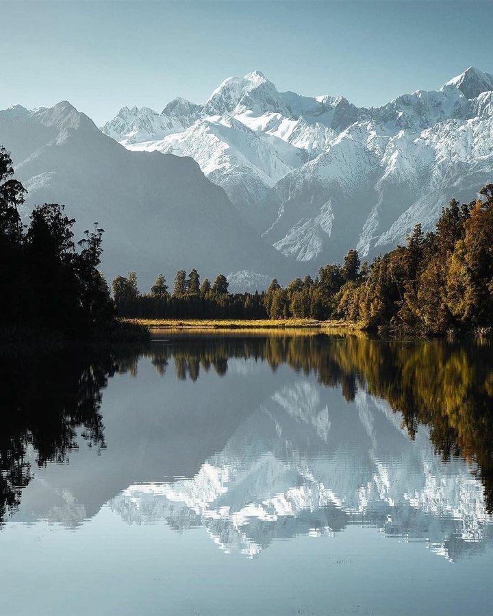 Paysage serein d'un lac entouré de montagnes se reflétant sur l'eau.