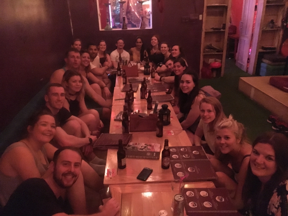 Groupe de personnes rassemblées autour d'une longue table à l'intérieur d'une pièce faiblement éclairée.