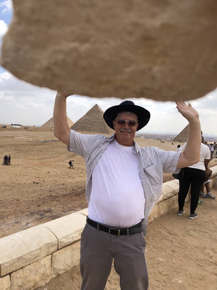 Personne posant avec une pyramide en arrière-plan.