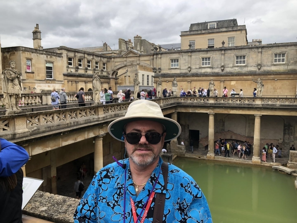 Une personne se tenant près d'une structure de bains historique avec une foule.