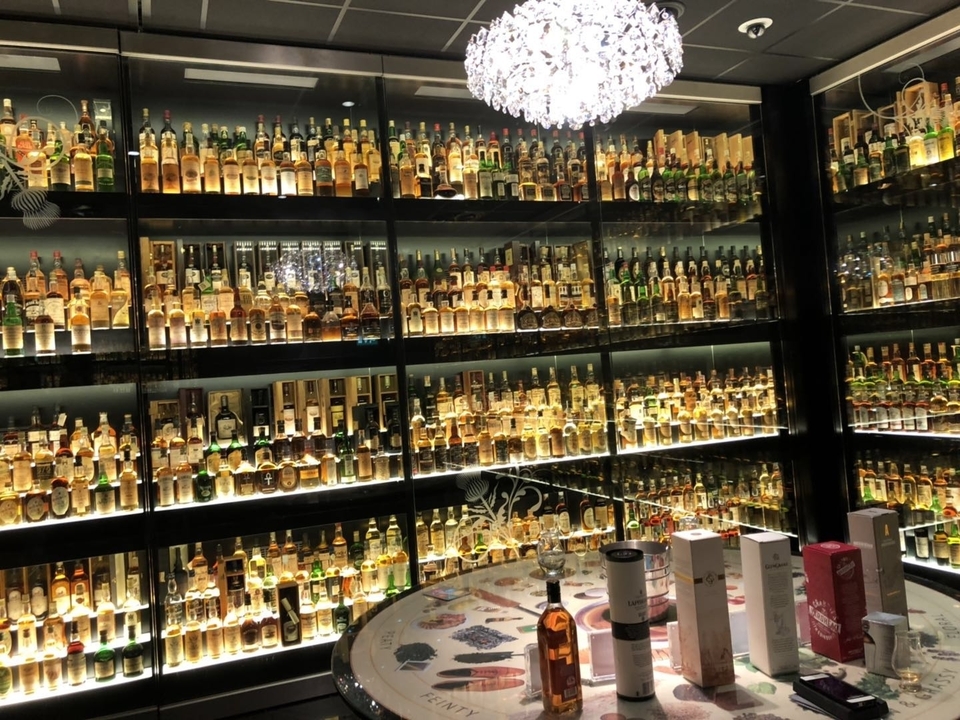 Une vitrine de magasin de spiritueux bien achalandée avec de nombreuses bouteilles.