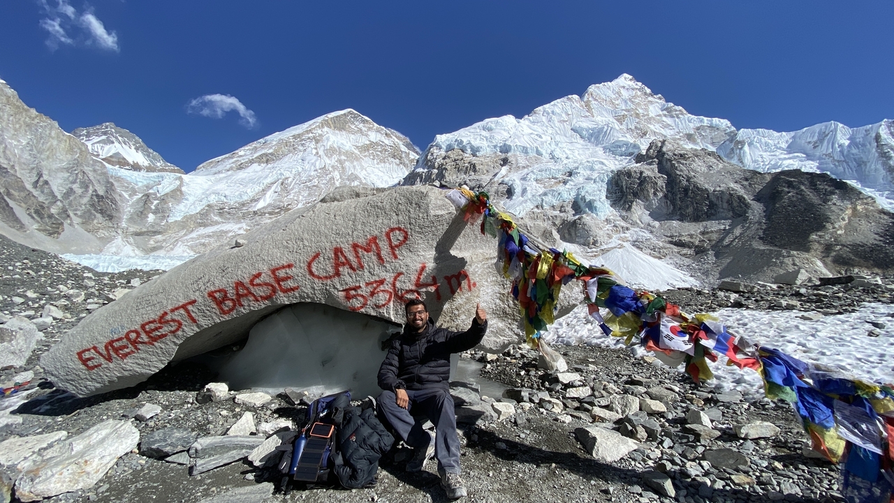 Une personne assise près du panneau du camp de base de l'Everest avec les montagnes.