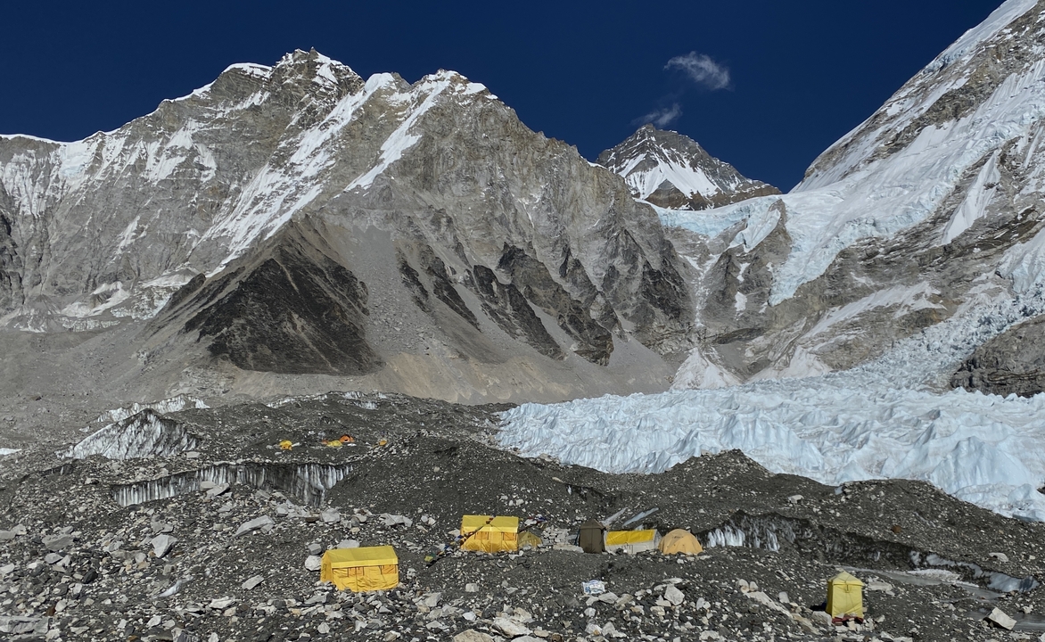 Un camp au pied d'un glacier avec des sommets couverts de neige.