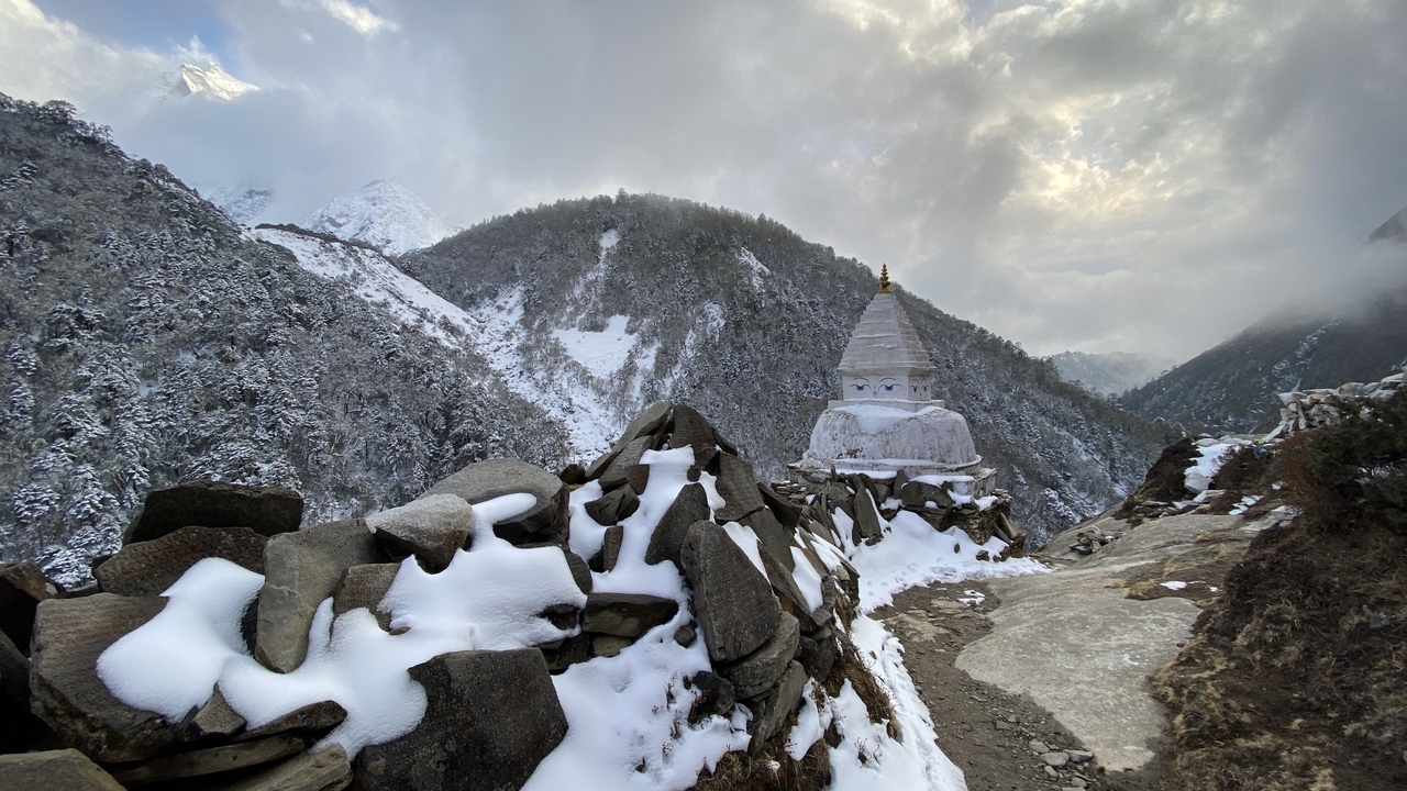 Un stupa entouré de collines et de rochers couverts de neige.