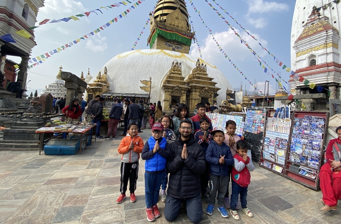 Un groupe de personnes devant un grand stupa avec des drapeaux colorés.