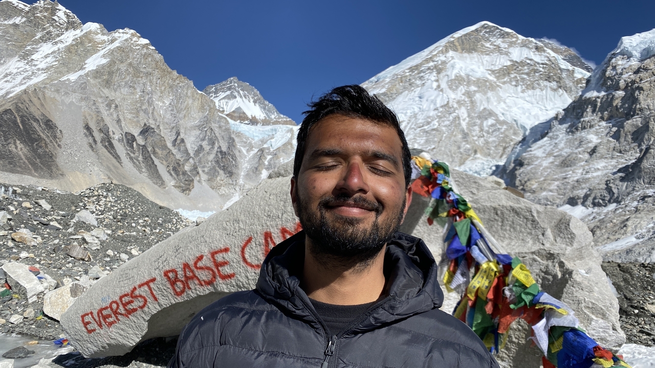 Gros plan d'une personne souriante avec le camp de base de l'Everest en arrière-plan.