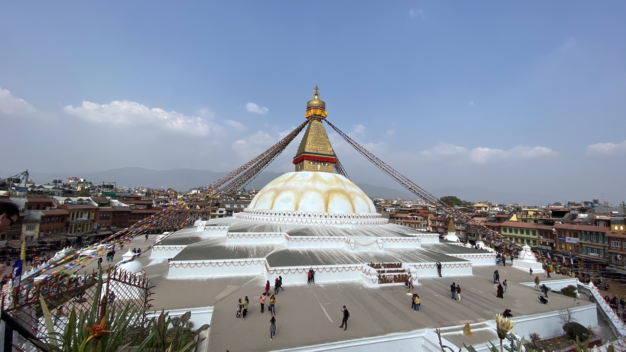 Un grand stupa avec des drapeaux entouré d'un paysage urbain.